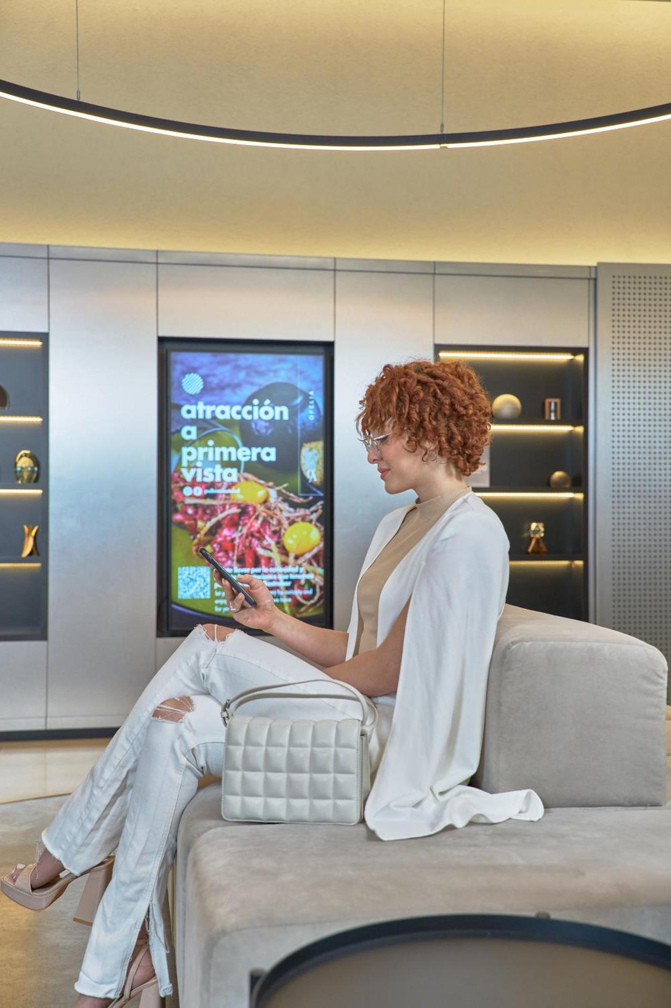Pullman Santiago Vitacura Exterior foto A woman using a mobile phone to interact with a digital signage display